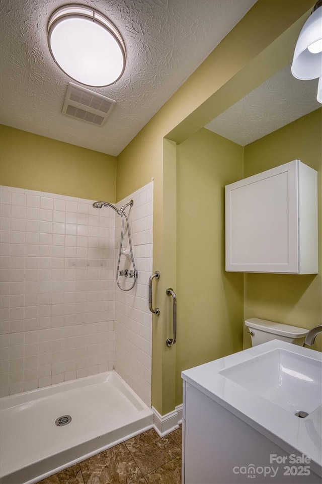 bathroom featuring sink, a tile shower, and a textured ceiling