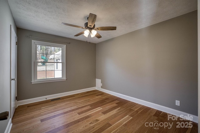 empty room featuring ceiling fan, wood-type flooring, and a textured ceiling