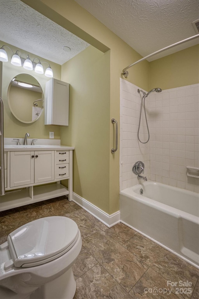 full bathroom featuring vanity, tiled shower / bath combo, toilet, and a textured ceiling