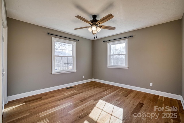 spare room with a textured ceiling, ceiling fan, and light wood-type flooring