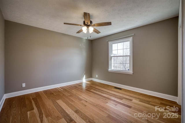 spare room featuring ceiling fan, light hardwood / wood-style floors, and a textured ceiling