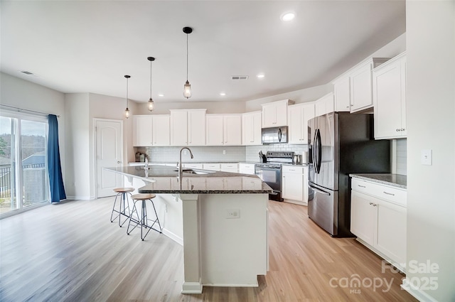 kitchen featuring a kitchen island with sink, white cabinetry, light hardwood / wood-style flooring, and appliances with stainless steel finishes