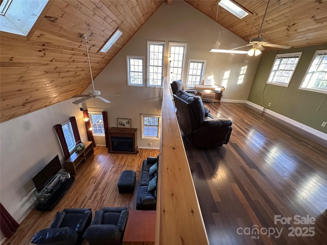 unfurnished living room with ceiling fan, a skylight, high vaulted ceiling, dark hardwood / wood-style flooring, and wooden ceiling