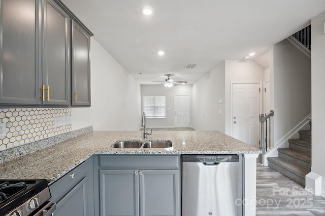 kitchen featuring sink, appliances with stainless steel finishes, kitchen peninsula, ceiling fan, and decorative backsplash