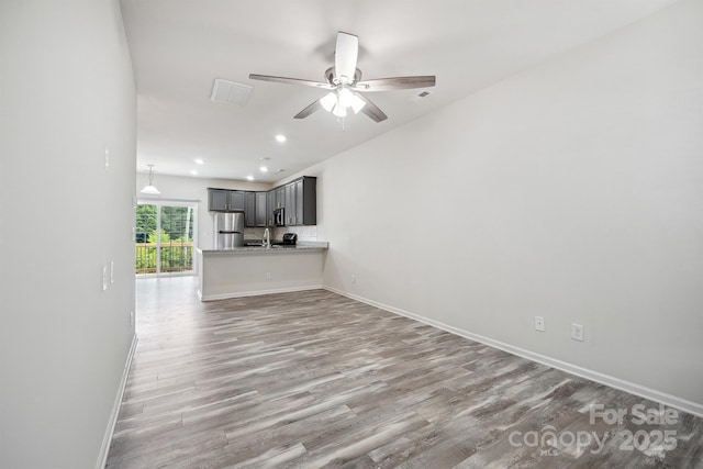 unfurnished living room with hardwood / wood-style flooring, sink, and ceiling fan