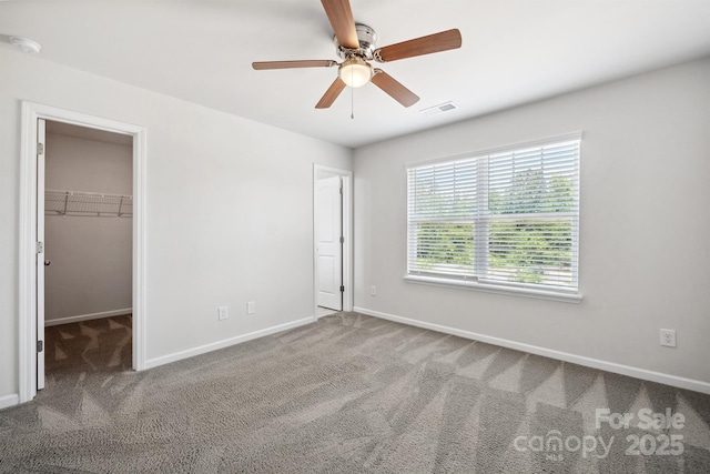 unfurnished bedroom featuring carpet flooring, ceiling fan, and a spacious closet