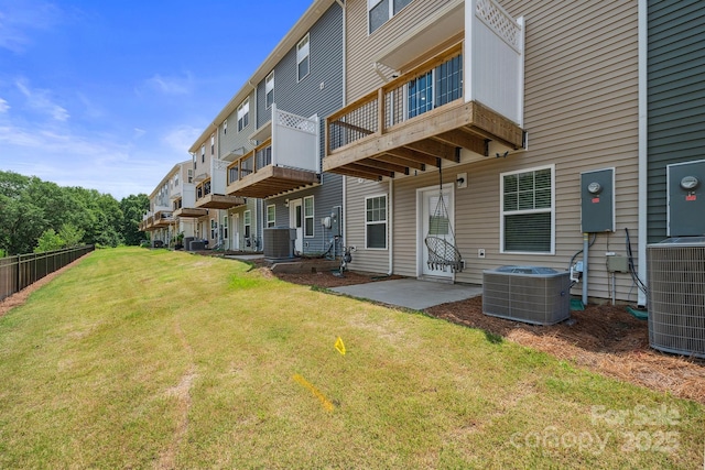 back of property with a lawn, central air condition unit, and a patio area