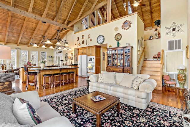 living room with high vaulted ceiling, wood-type flooring, ceiling fan, wooden ceiling, and beam ceiling