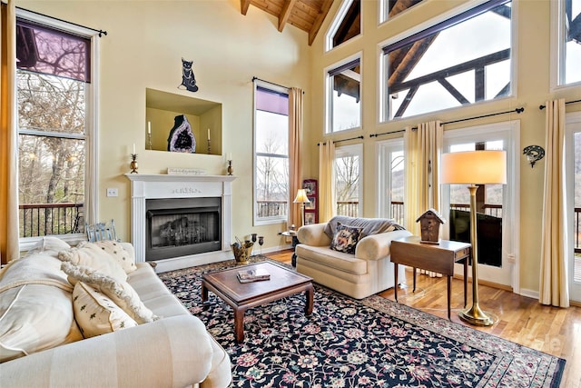 living room with wood-type flooring, high vaulted ceiling, beamed ceiling, and a healthy amount of sunlight