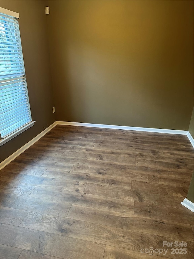 unfurnished room featuring baseboards and dark wood finished floors