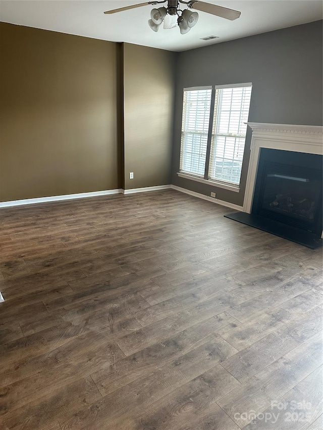 unfurnished living room featuring dark wood-type flooring, a ceiling fan, and visible vents