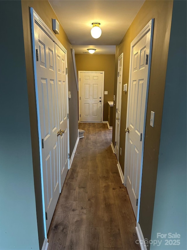 hallway with baseboards and dark wood-type flooring