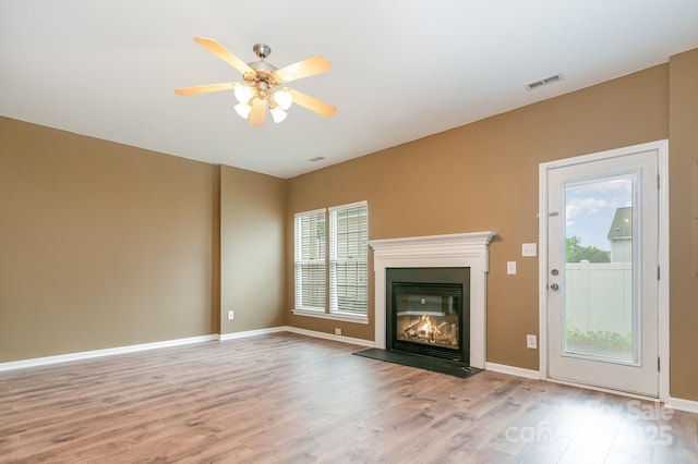 7117 Flying Scotsman Dr, Charlotte, NC 28213 - unfurnished living room with wood finished floors, a ceiling fan, a glass covered fireplace, and baseboards