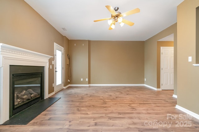 7117 Flying Scotsman Dr, Charlotte, NC 28213 - unfurnished living room featuring light wood-style floors, ceiling fan, a glass covered fireplace, and baseboards