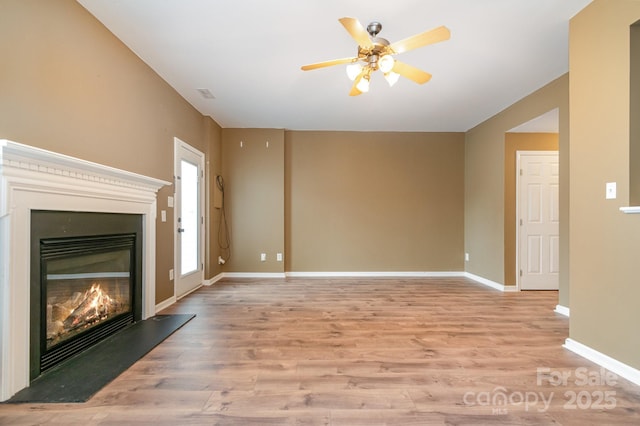 7117 Flying Scotsman Dr, Charlotte, NC 28213 - unfurnished living room with a glass covered fireplace, light wood-type flooring, a ceiling fan, and baseboards