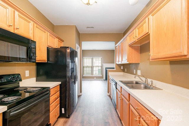 7117 Flying Scotsman Dr, Charlotte, NC 28213 - kitchen with black appliances, a sink, wood finished floors, light brown cabinets, and light countertops
