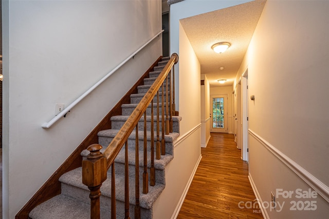 stairway featuring hardwood / wood-style floors and a textured ceiling