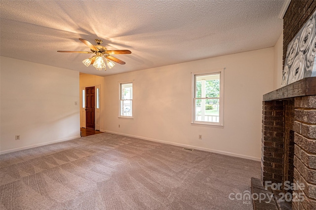 unfurnished living room featuring a brick fireplace, a textured ceiling, ceiling fan, and carpet flooring