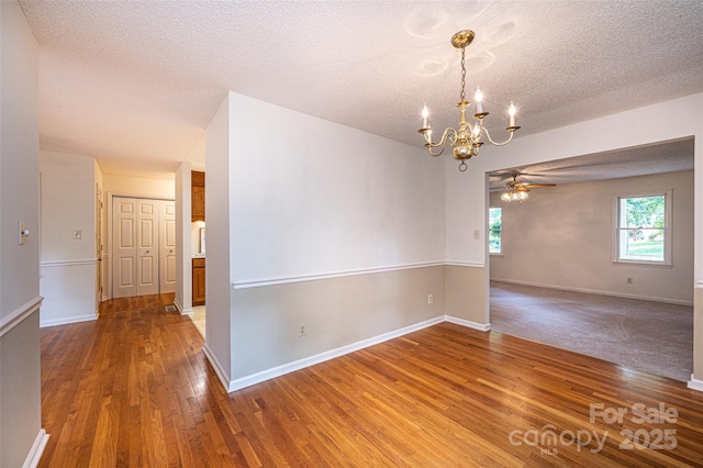 spare room featuring hardwood / wood-style floors, ceiling fan with notable chandelier, and a textured ceiling