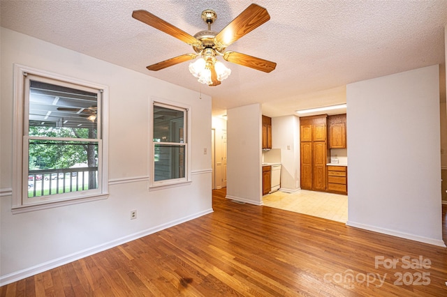 unfurnished living room with ceiling fan, a textured ceiling, and light wood-type flooring