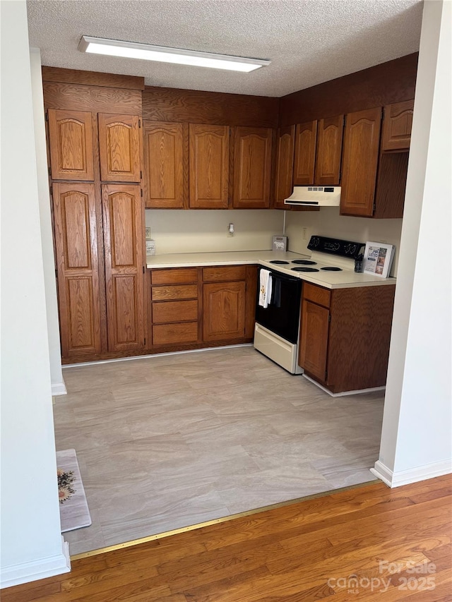 kitchen with white electric stove, light wood-type flooring, and a textured ceiling