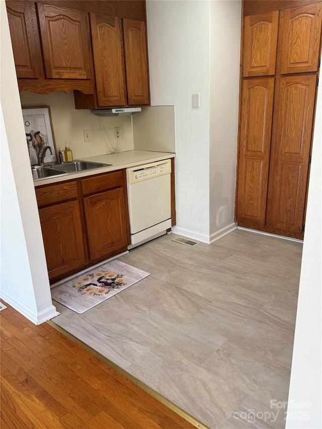 kitchen with white dishwasher, sink, and light hardwood / wood-style flooring