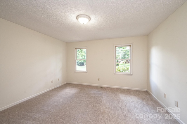 carpeted empty room with a textured ceiling