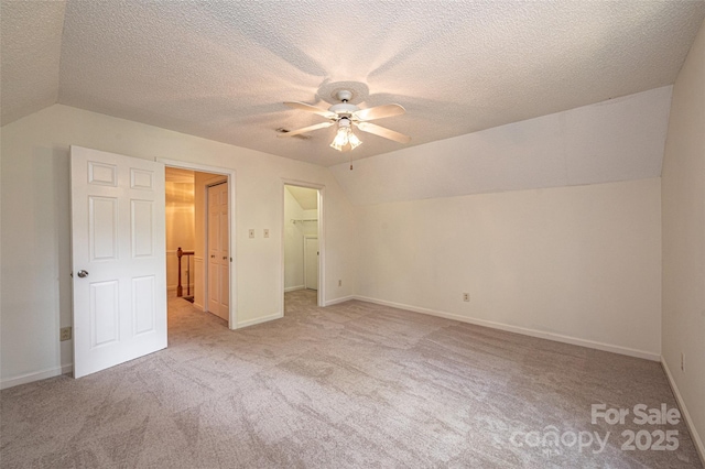 unfurnished bedroom featuring vaulted ceiling, a spacious closet, ceiling fan, and a closet