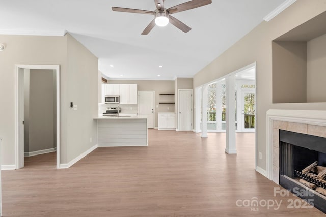 living room with a ceiling fan, baseboards, light wood-style flooring, recessed lighting, and a tile fireplace