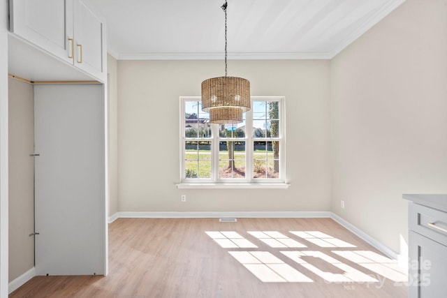 unfurnished dining area featuring a notable chandelier, baseboards, crown molding, and light wood-style floors