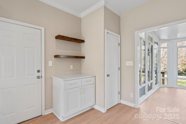 doorway to outside featuring baseboards, crown molding, and light wood-style floors