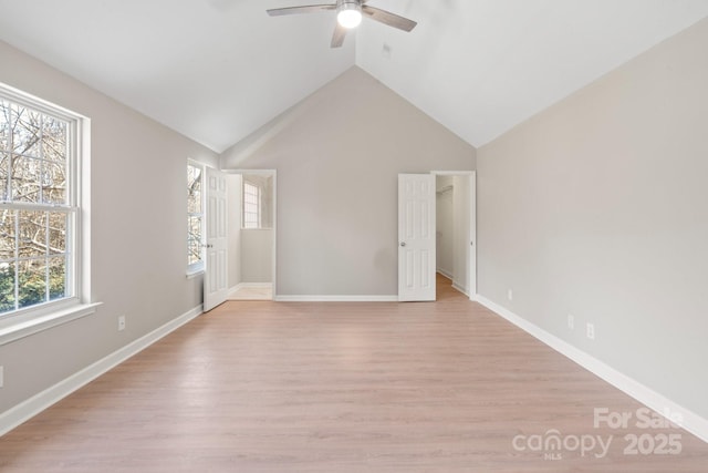 unfurnished room with lofted ceiling, light wood-style floors, baseboards, and ceiling fan