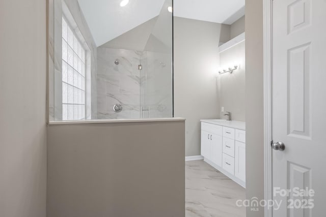 bathroom with baseboards, walk in shower, lofted ceiling, marble finish floor, and vanity