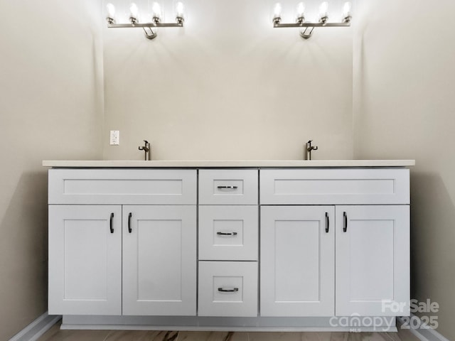 full bathroom with a sink, baseboards, and double vanity