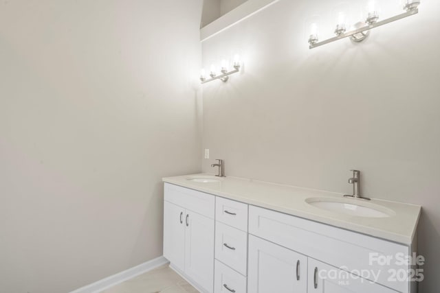 bathroom with double vanity, baseboards, and a sink