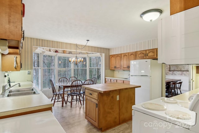 kitchen featuring a kitchen island, sink, a chandelier, white fridge, and range