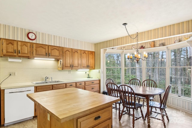 kitchen featuring pendant lighting, butcher block countertops, sink, a center island, and white dishwasher