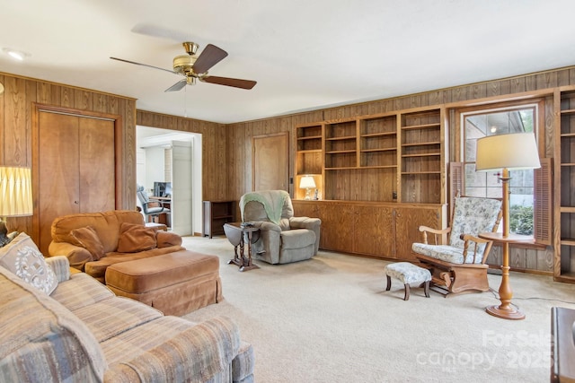 living room with ceiling fan, wooden walls, and carpet