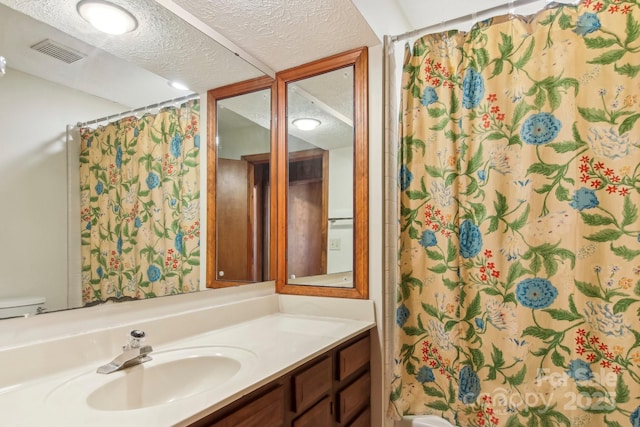 bathroom featuring vanity, curtained shower, a textured ceiling, and toilet