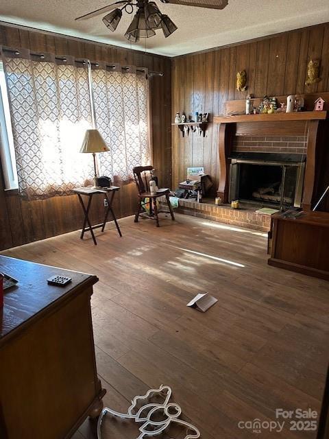 sitting room with ceiling fan, wood-type flooring, a textured ceiling, and wood walls