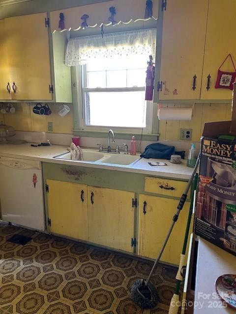 kitchen with white dishwasher, dark tile patterned flooring, and sink