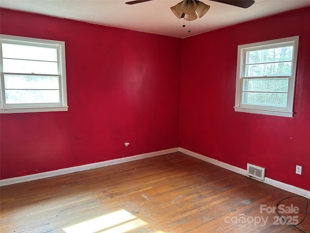 empty room with a healthy amount of sunlight, hardwood / wood-style floors, and ceiling fan