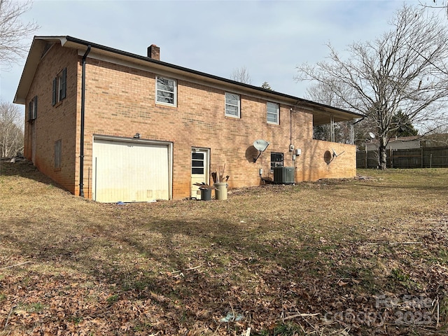 back of property with a garage, a yard, and central air condition unit