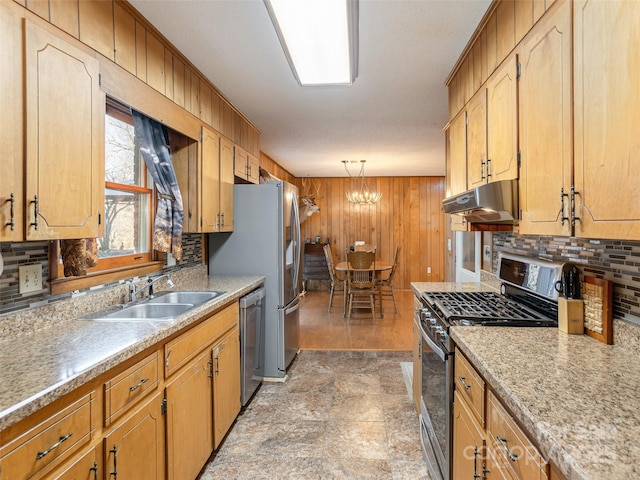 kitchen featuring sink, tasteful backsplash, hanging light fixtures, appliances with stainless steel finishes, and wooden walls