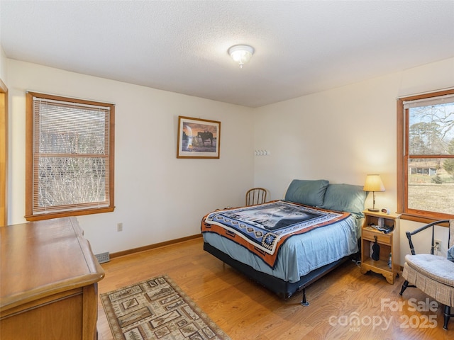 bedroom featuring light hardwood / wood-style floors and a textured ceiling