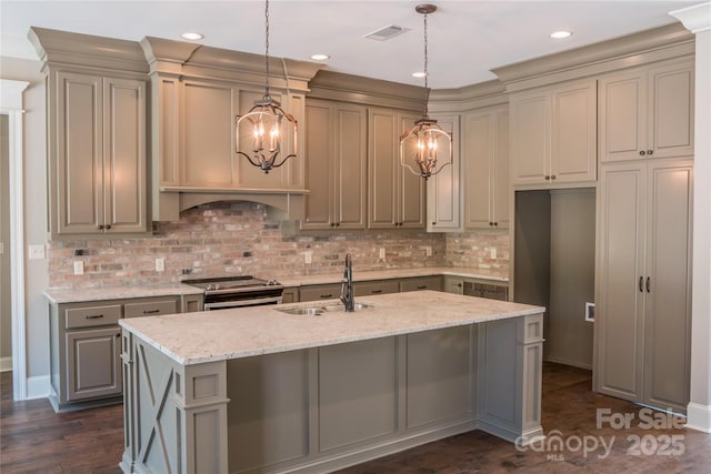 kitchen with a kitchen island with sink, sink, stainless steel range with electric cooktop, and light stone counters