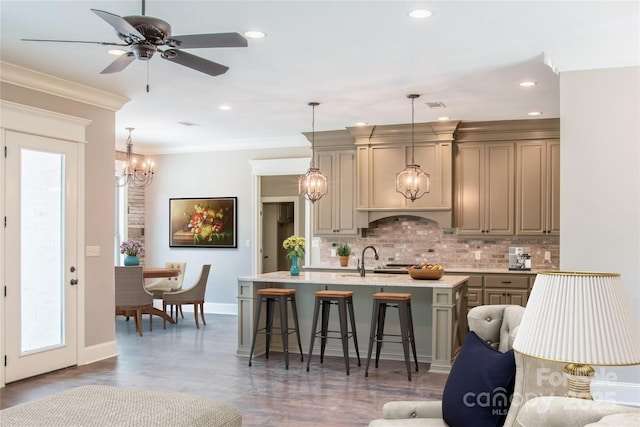 kitchen featuring a kitchen island with sink, crown molding, tasteful backsplash, and a breakfast bar