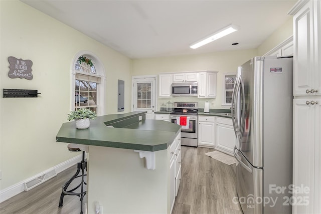 kitchen featuring white cabinetry, stainless steel appliances, light hardwood / wood-style floors, and a breakfast bar area