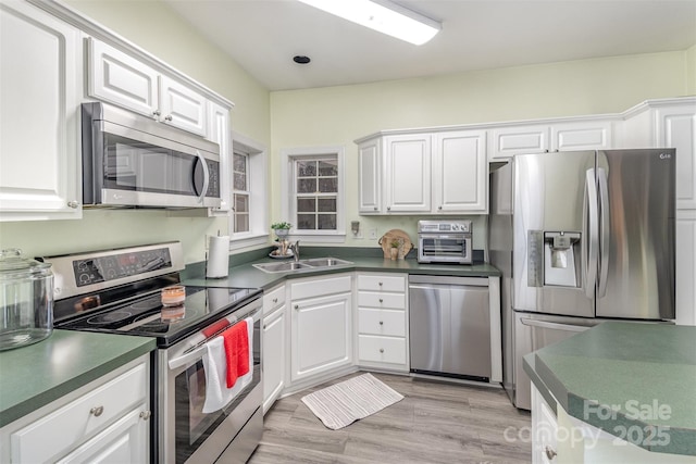 kitchen featuring white cabinetry, sink, light hardwood / wood-style flooring, and stainless steel appliances