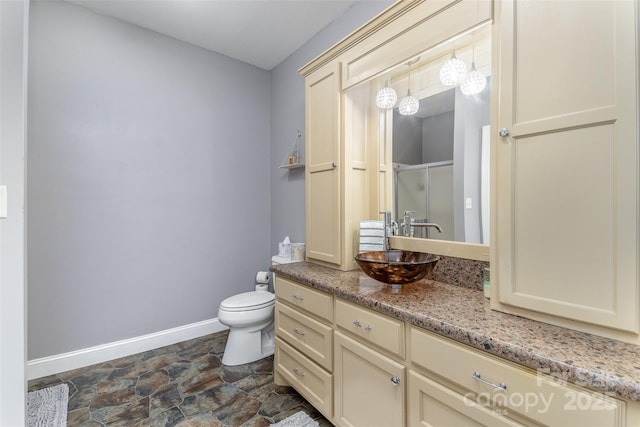 bathroom featuring a shower with door, vanity, and toilet